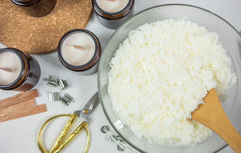 Mixing bowl filled with soy wax next to some homemade candles