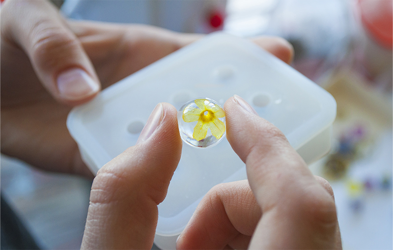 Small yellow flower cast in epoxy resin, with silicone mould in the background