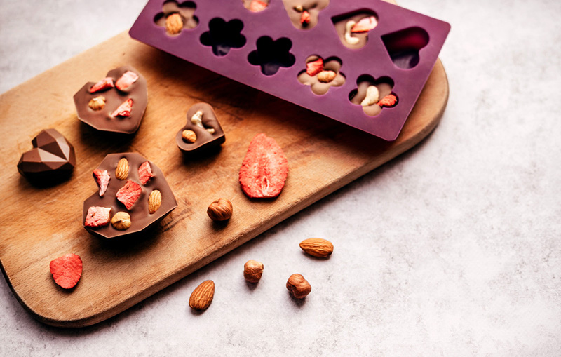 Chocolate treats next to silicone mould filled with chocolate castings