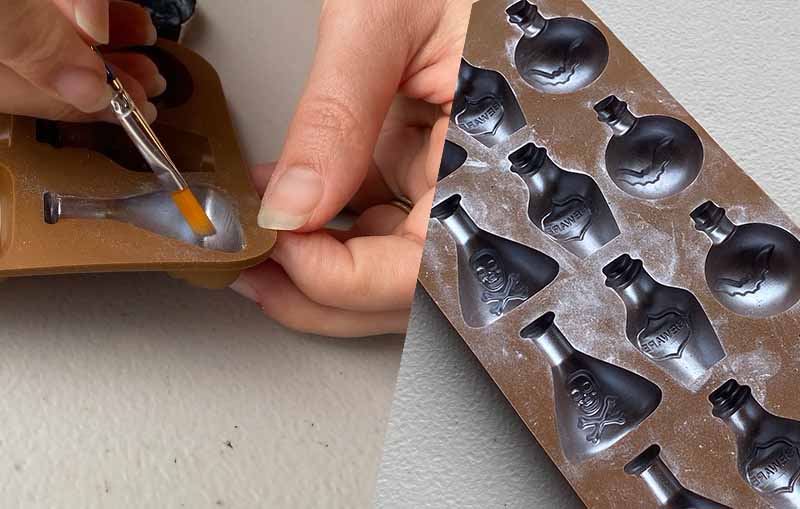 Brushing edible silver powder into the cavities of a silicone mould to make halloween chocolate candy