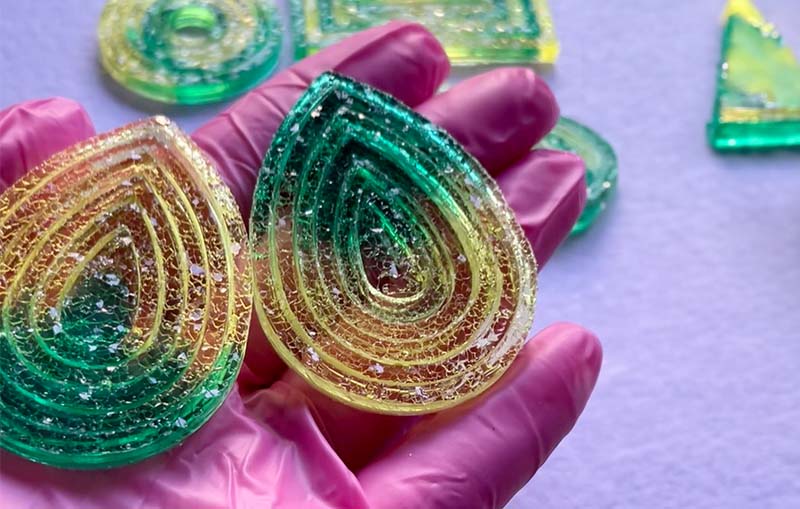 A persons hand holding some colourful resin artwork with a decorative design