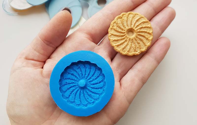 Silicone putty mold of a cookie, placed on a persons hand