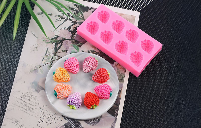 Clay for silicone molds - Pink silicone mold with strawberry shapes and colorful clay strawberries on a plate.