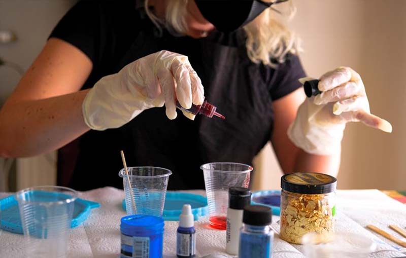 Epoxy resin vs UV resin safety – a crafter wearing gloves and a mask while adding pigment to resin, ensuring proper protection during crafting.